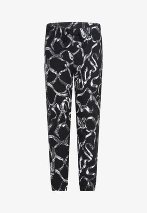 Melnas bikses ar abstraktu baltu rakstu, kas atgādina savītas līnijas, izgatavotas no mīkstas auduma, ar elastīgu jostu un sašaurinātiem stiprinājumiem.