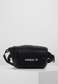 Černá taška Adidas vyrobená z nylonu, s texturovaným fleece předním dílem, nastavitelným popruhem, zipovým uzávěrem a bílým logem.