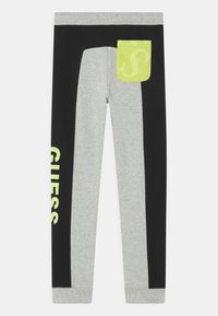 Grijze en zwarte legging met een contrasterende neon groene zak. Heeft grote "GUESS" tekst in het geel aan de linkerkant. Van katoenmix materiaal.