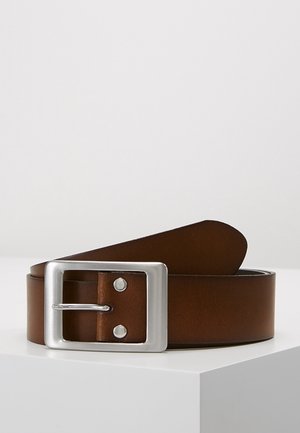 Ceinture en cuir marron enroulée sur une surface blanche avec une grande boucle rectangulaire en métal argenté et deux rivets métalliques près de la boucle.