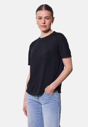 T-shirt nera a maniche corte con scollatura rotonda, realizzata in un tessuto morbido. Orlo leggermente curvato, indossato con jeans di denim azzurri.