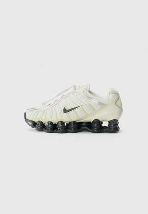 Biały i jasnozielony but sportowy z czarną segmentowaną podeszwą sprężynową i logo Nike z boku, pokazany z profilu na jednolitym tle.