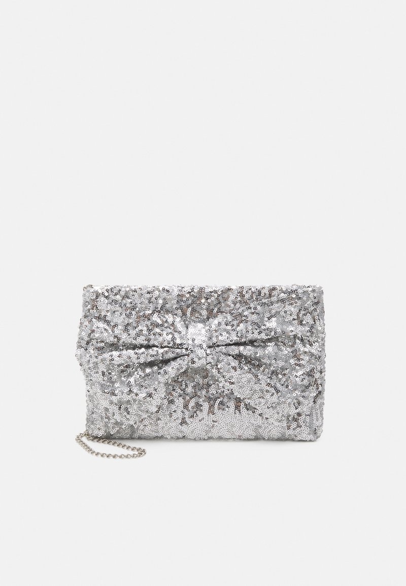 Pochette argentée à sequins avec un grand nœud décoratif et une petite chaîne argentée sur un fond clair uni.