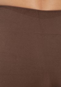 Bruin ribgebreid materiaal met een gladde textuur, voorzien van een brede tailleband en subtiele glans, geschikt voor actieve of casual kleding.