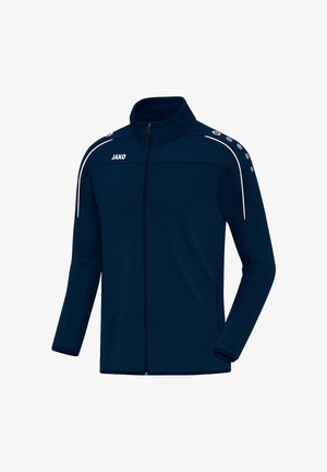 Navy zip-up jacket made of soft fabric, featuring a high collar, white accents, and shoulder buttons. Brand logo "JAKO" on the front.