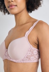 Light pink bra featuring a smooth padded front, lace sides, and adjustable straps with a scalloped edge detailing.
