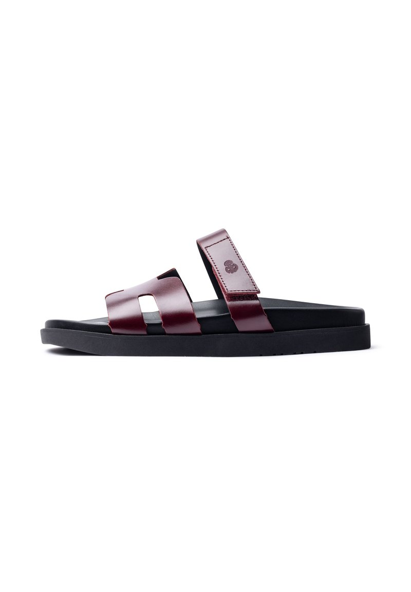 Maroon leather sandals with two wide straps, featuring cutout designs. Black rubber sole, flat profile, and embossed logo detail.