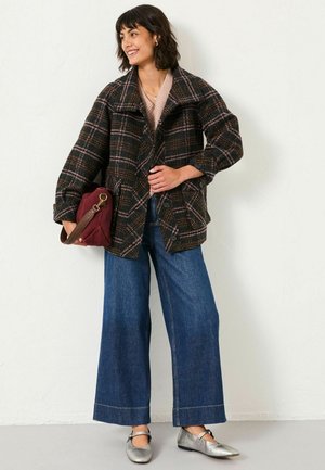 Plaid jacket with a black, brown, and pink color scheme, oversized fit, and button closure, paired with wide-leg blue jeans and silver shoes.