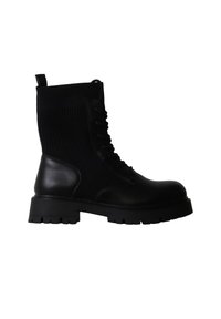 Botte de combat noire à lacets avec semelle épaisse et partie supérieure en tissu côtelé, vue de côté sur fond blanc.