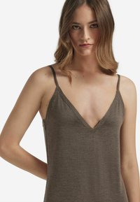 Brun, ärmlös topp med V-ringning. Tillverkad av mjukt tyg, med tunna axelremmar och en subtil, slät textur.