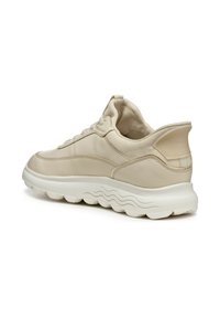Baskets beiges avec une tige en cuir lisse, des accents texturés, des lacets ronds et une épaisse semelle blanche ondulée offrant un bon amorti.