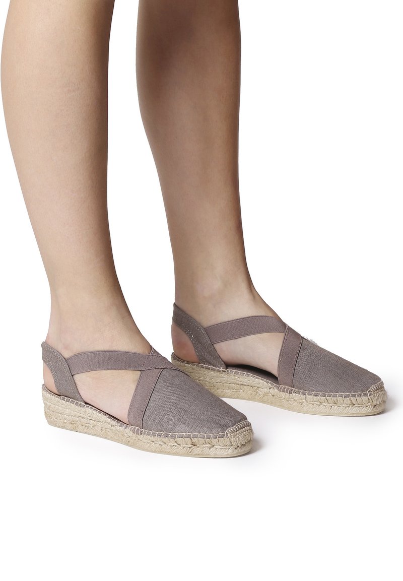 Espadrillas in tessuto grigio con suola in juta a zeppa, dotate di cinturini incrociati e design con tallone aperto. Materiale leggero e traspirante.