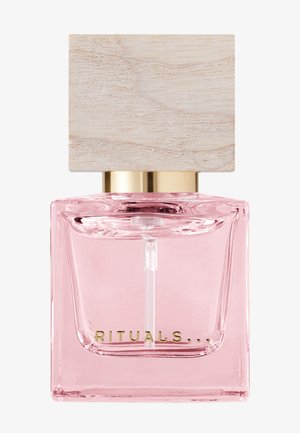 Glas parfume flaske med en lyserød væske, et guldmetalbånd og en kvadratisk træprop. Har en gennemsigtig spraydyse.