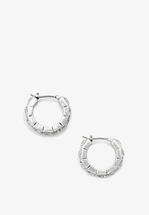 Orecchini a cerchio in argento con una finitura testurizzata, caratterizzati da cristalli trasparenti incastonati lungo il bordo esterno. Forma rotonda, chiusura con fermaglio standard.