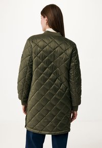 Olijfgroene gequiltede jas met ruitpatroon, geribbelde manchetten en een lichtgekleurde kraag. Beschikt over zijslits voor bewegingsgemak.