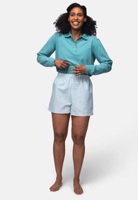 Türkise Langarm-Poloshirt mit Knopfdetail, kombiniert mit hellblauen gestreiften Shorts mit elastischem Bund und kleinem Logo.