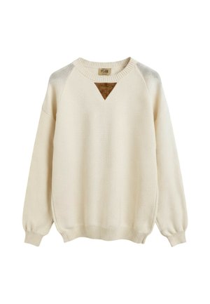 Maglione lavorato a maglia color crema con maniche lunghe, polsini e orlo a costine, e una piccola toppa triangolare marrone sotto la scollatura.