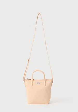 Borsa piccola beige con due manici corti, tracolla lunga regolabile e logo a coccodrillo sul davanti.