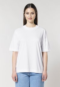 Witte katoenen t-shirt met korte mouwen, losse pasvorm en een ronde halslijn, gecombineerd met lichtblauwe spijkerbroek.