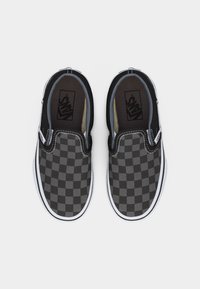 Ζευγάρι παπουτσιών Vans slip-on με καρό σχέδιο σε μαύρο και γκρι χρώμα, με λευκές σόλες, εμφανιζόμενα από πάνω σε λευκό φόντο.