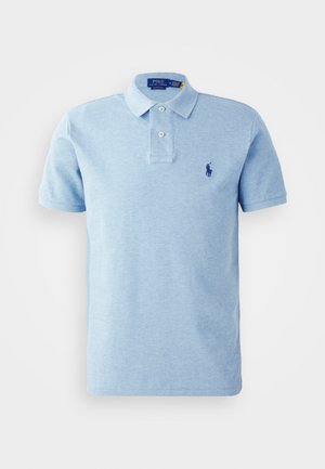 Polo de color azul claro, confeccionado en una tela suave, que cuenta con una tapeta de tres botones y un pequeño logo azul oscuro en el lado izquierdo del pecho.