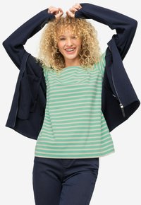 T-shirt a righe verde e beige con collo rotondo, abbinato a una giacca zip nera scura con tasche laterali. Tessuto dalla consistenza liscia.