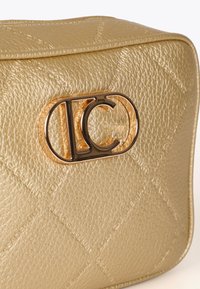 Borsa in oro testurizzato con un prominente chiusura a logo dorato scuro sul davanti, su uno sfondo bianco.