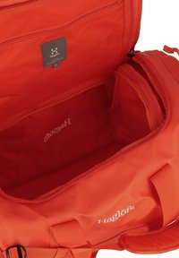 Borsa a mano rossa in tessuto resistente, con un ampio interno, tasca interna con zip e logo in evidenza. Presenta cinturini regolabili e zip sicuri.