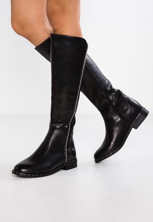 Black leather knee-high boots featuring a side zipper and studded accents along the outer seam. Flat heel and smooth texture.
