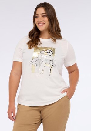 Camiseta blanca de algodón con un gráfico de dos figuras estilizadas en negro y dorado, de manga corta y un corte relajado, combinada con pantalones beige.