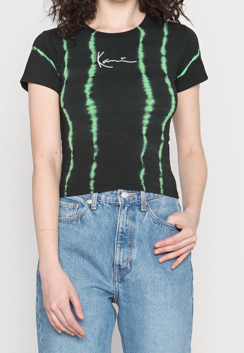 Black cotton t-shirt with green tie-dye stripes, featuring a white cursive logo. Fitted design with short sleeves and a cropped length.