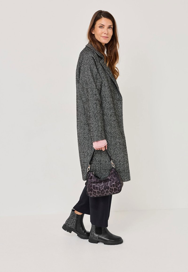 Abrigo largo gris texturizado, acentuado con mangas rosas, pantalones amplios negros y botines negros brillantes, acompañados de un bolso de mano con estampado de leopardo.