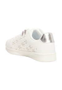Witte sneaker met een geperforeerd bloemmotief, zilveren accent bij de hak, en een gladde textuur, met een ronde neus en platte zool.