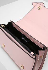 Różowa torebka typu crossbody o teksturowanej powierzchni z złotymi akcentami i czarną kieszonką na suwak w środku. Posiada zapięcie na klapkę oraz gładkie wykończenie wnętrza.