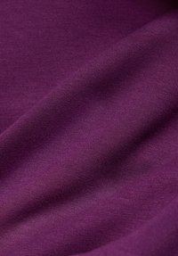 Lila Stoff mit einer glatten Textur, fließenden Drapierungen und einem subtilen Schimmer. Das Material weist ein feines Strickmuster auf.
