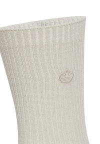 Bež čarape s rebrastom teksturom, s malim izvezenim logotipom na gležnju; suptilan, diskretan dizajn.