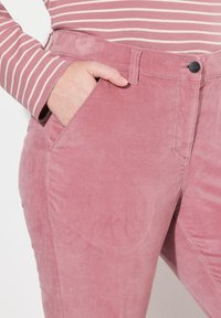 Rosa kordfl carbyxor med en slät yta, sidoficka och knappstängning. Har en något avsmalnande design och en subtil lyster.