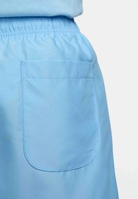 Pantalon bleu clair à taille élastique avec une grande poche carrée à l'arrière et des coutures propres et simples sur tissu uni.