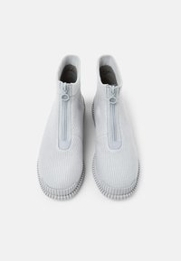 Ljust gråa slip-on skor i texturerat tyg med dragkedja framtill och gummisula, med rund tå och ribbad detalj.