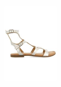 Sandalias planas metálicas plateadas con múltiples correas, hebilla ajustable en el tobillo y una plantilla marrón lisa. Diseño minimalista.