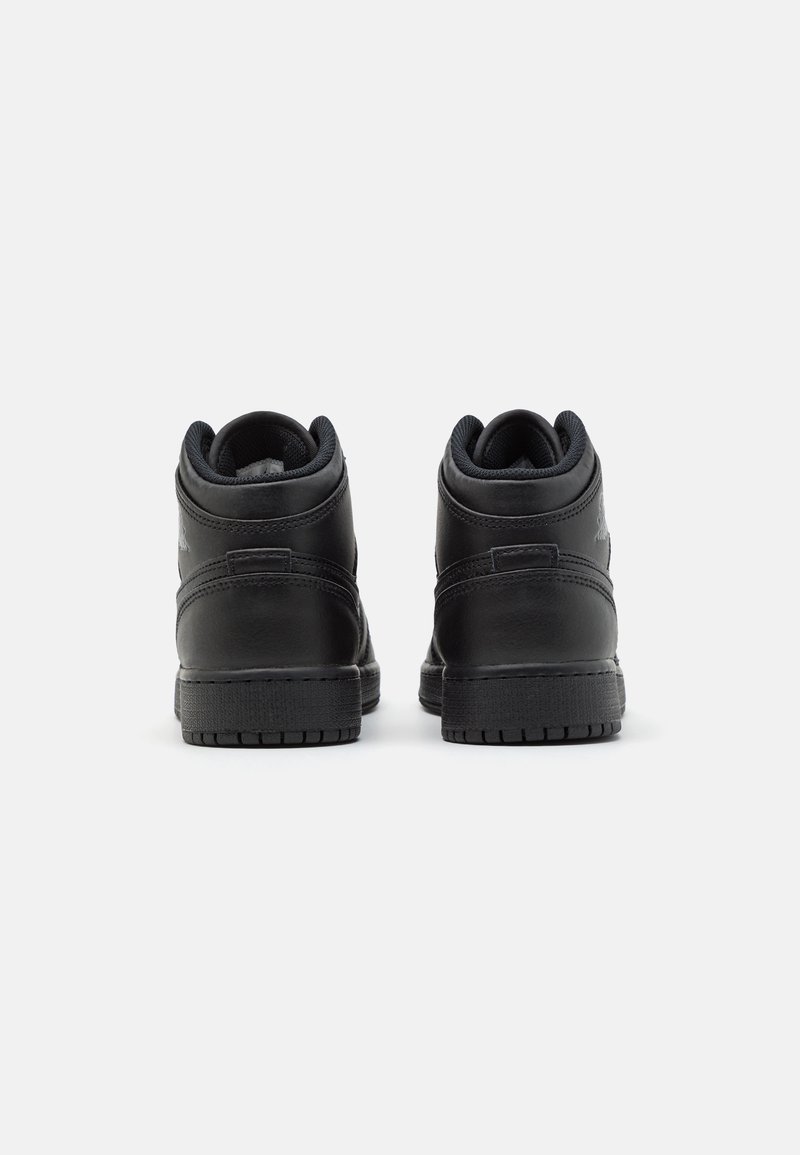 Baskets montantes noires avec un extérieur en cuir lisse, une semelle en caoutchouc texturé et un col rembourré. Présente un design minimaliste et des détails de couture.