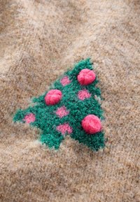 Maglione lavorato a maglia con sfondo beige testurizzato che presenta un disegno di un albero di Natale verde decorato con ornamenti a pon-pon rosa e accenti rosa.