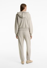 Light gray hoodie and matching joggers in soft fabric. Hoodie features a large hood, while joggers have an elasticated waist and back pocket.
