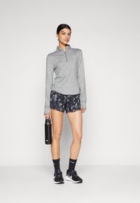 Grå hettegenser med glidelås og lang erm, marineblå mønstrede shorts, svarte joggesko, mørke sokker og en svart vannflaske. Uformell sportslig antrekk.