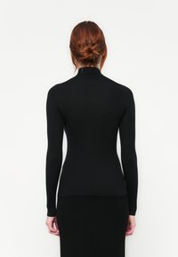Must värviline soonikkoesed turtleneck särk pikkade varrukatega, külge liibuv kuju ja kõrge kaelus, valmistatud venivast kudumaterjalist.