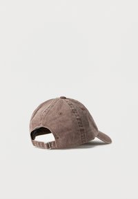 Καφέ βαμβακερό καπέλο μπέιζμπολ με ρυθμιζόμενο λουράκι, φαίνεται από πίσω με φόντο ένα απλό φωτεινό φόντο.