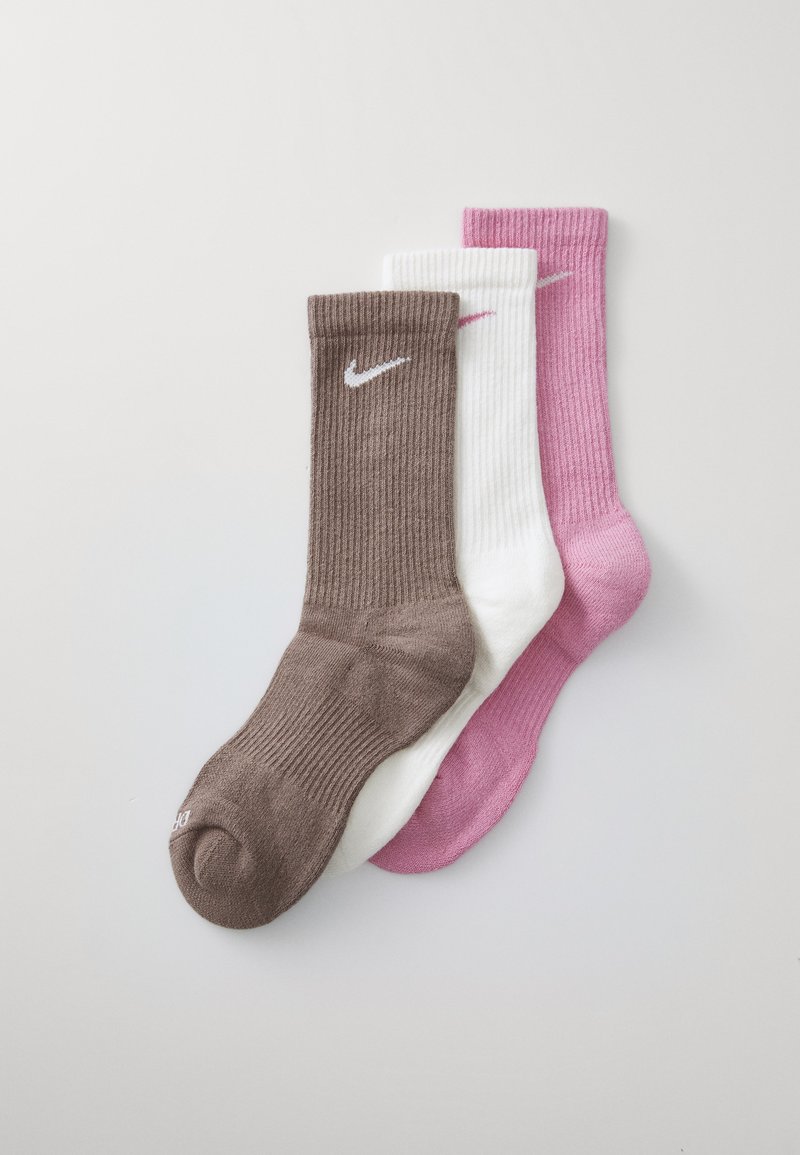 Tři páry žebrovaných ponožek do kotníku v hnědé, bílé a růžové barvě. Na hnědých ponožkách je bílé logo Nike. Měkká textura, standardní tvar ponožky.