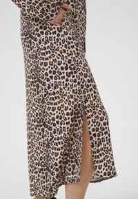 Rochie maxi cu imprimeu leopard din material moale, cu mâneci lungi, buzunare laterale și o fanta până la coapsă pe o parte.
