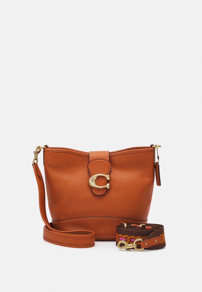 Braune Lederhandtasche mit goldenen Beschlägen, einschließlich eines Verschlusses mit einem "C"-Logo. Mit abnehmbarem Stoffgurt mit bunten Musterakzenten.