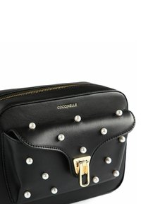 Borsa a tracolla in pelle nera con dettagli in perle, ferramenta dorata, chiusura con zip e patta frontale. Design compatto con una texture liscia.